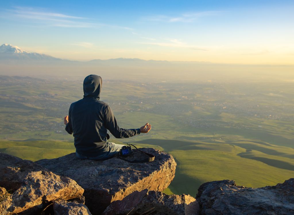 man sitting on the rock and meditating