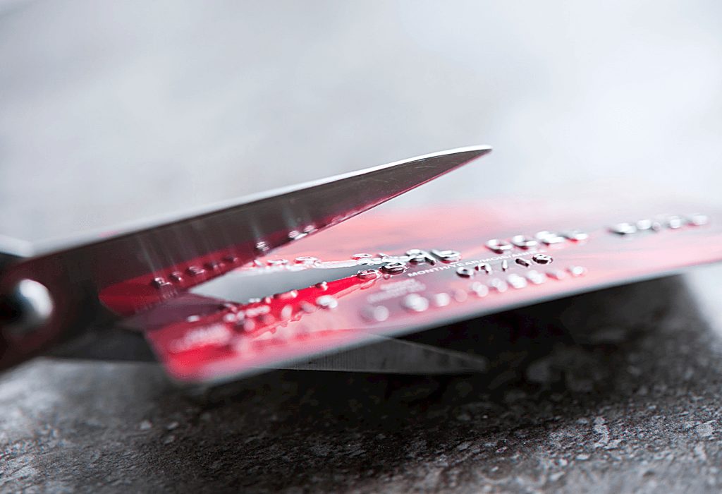 Scissors cutting credit card. This can be useful for making collar stays which is a great clothing hack for guys 