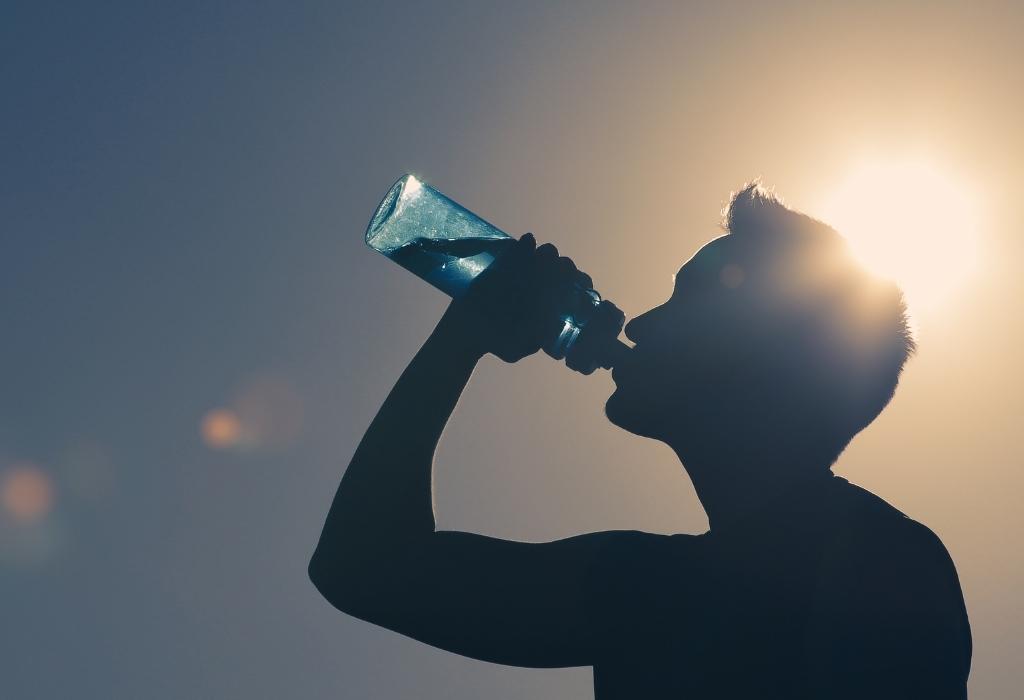 man drinking water in the sun - personal development goal 