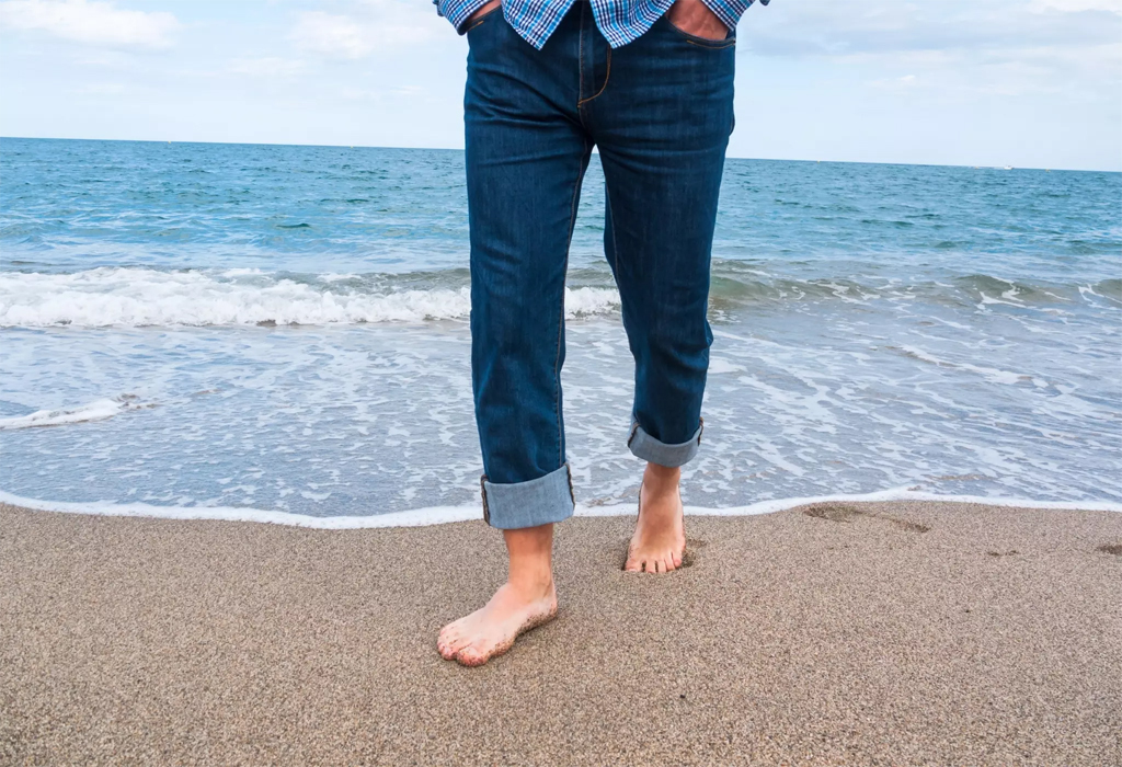 man in cuffed jeans walking the seashore