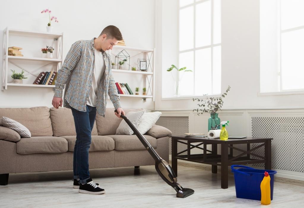 man vacuuming carpet doing housework chores